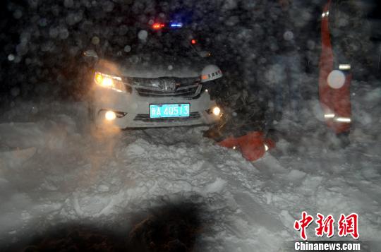 圖為消防人員跪在雪地里用鐵鍬鏟雪救援被困車輛?！±罱z